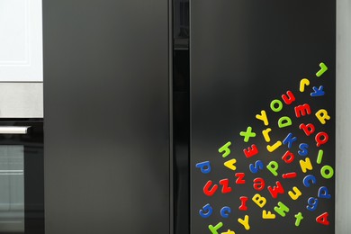 Photo of Many bright magnetic letters on fridge indoors. Learning alphabet