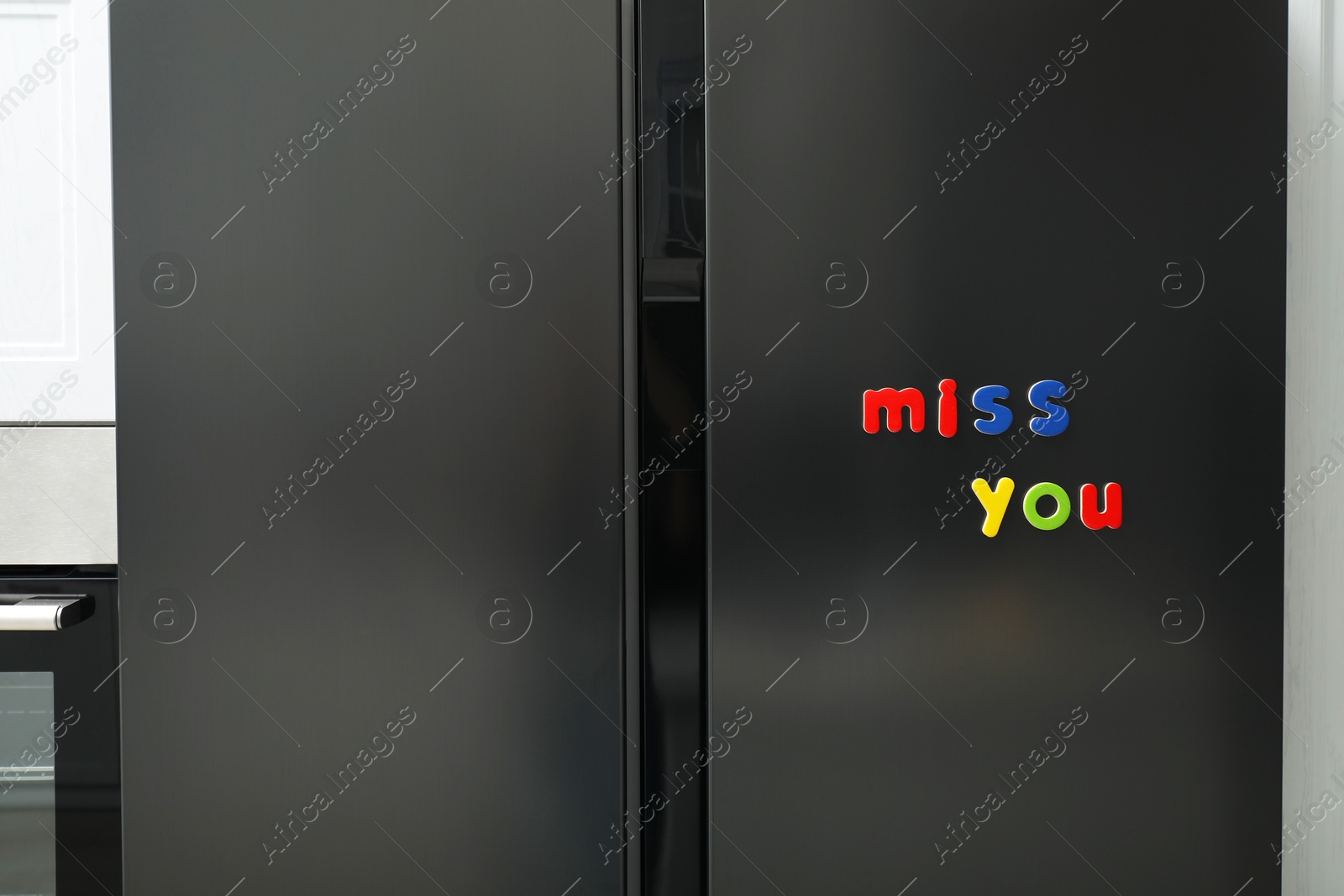 Photo of Phrase Miss You made of many bright magnetic letters on fridge indoors. Learning alphabet