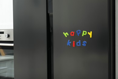 Words Happy Kids made of bright magnetic letters on fridge indoors. Learning alphabet