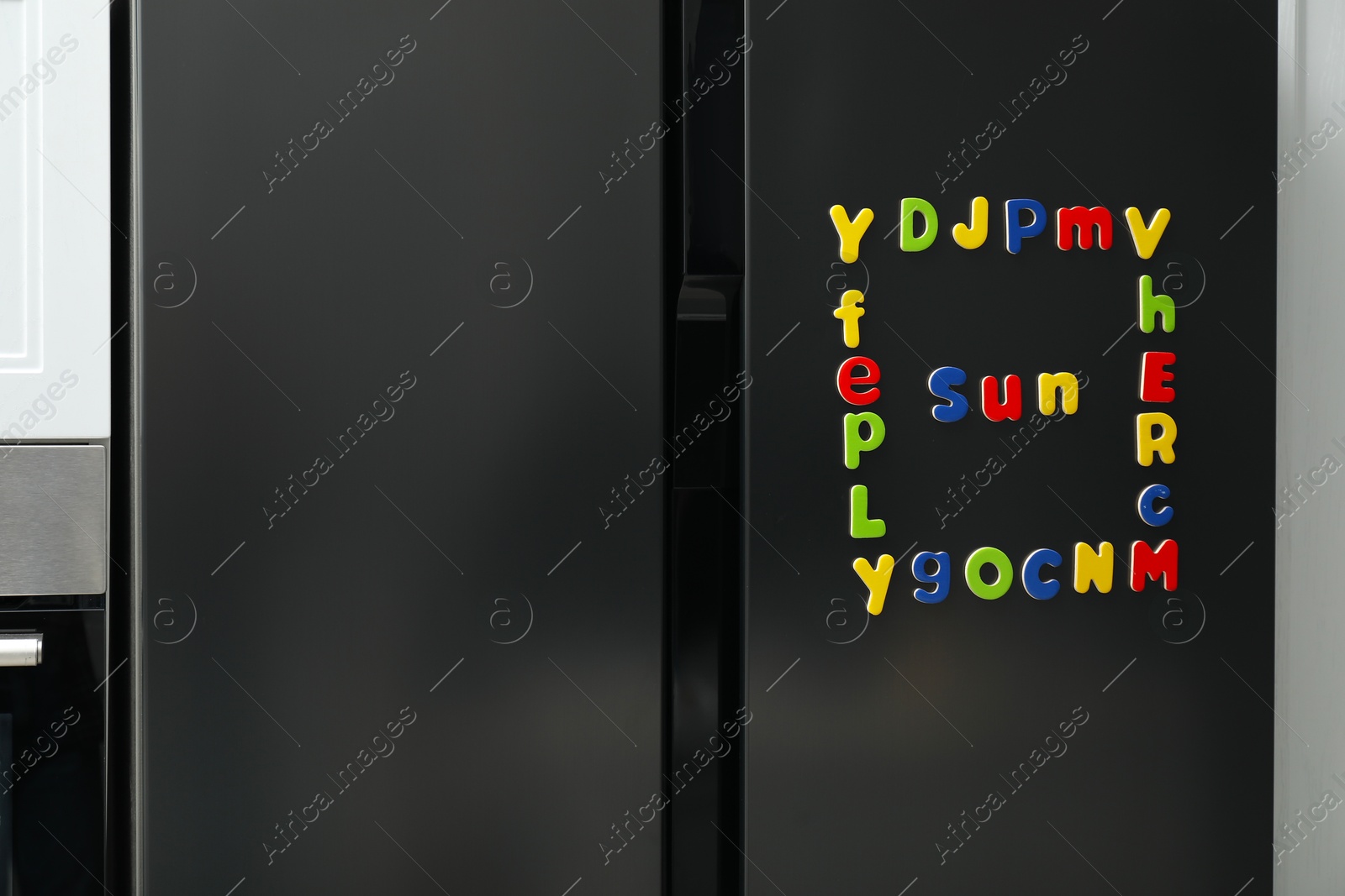 Photo of Word Sun and frame made of many bright magnetic letters on fridge indoors. Learning alphabet