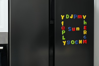 Word Sun and frame made of many bright magnetic letters on fridge indoors. Learning alphabet