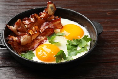 Tasty bacon, eggs and parsley in frying pan on wooden table, closeup