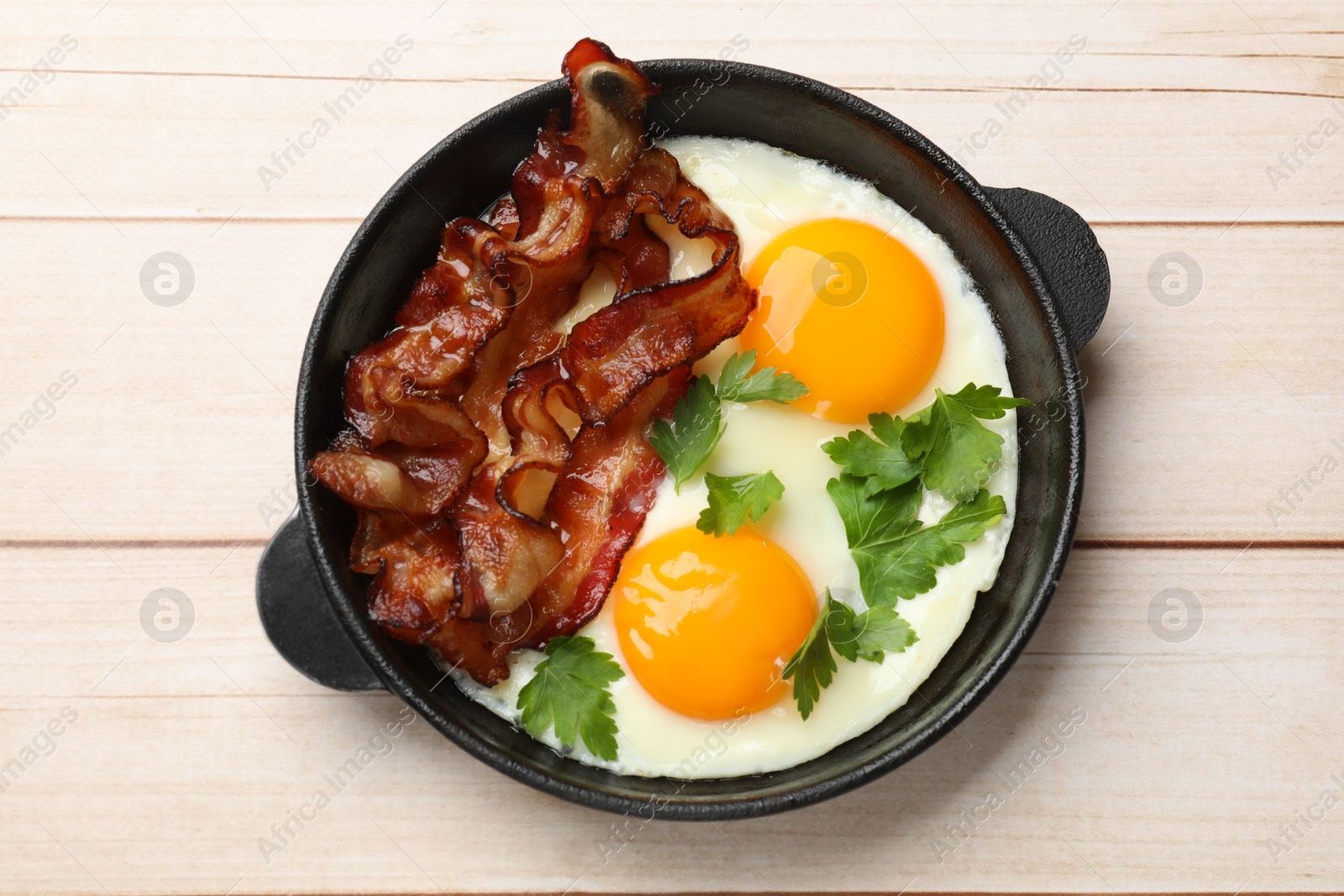 Photo of Tasty bacon, eggs and parsley on light wooden table, top view