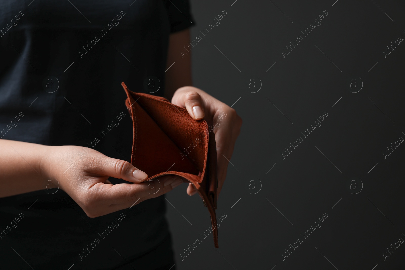 Photo of Woman with empty wallet on dark background, closeup