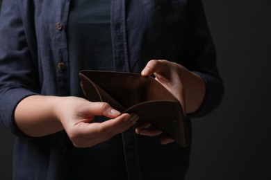 Photo of Woman with empty wallet on dark background, closeup