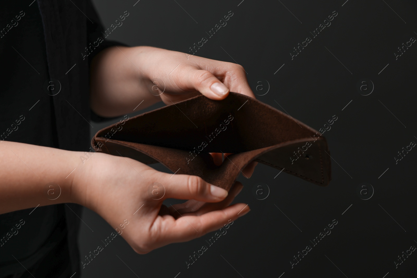 Photo of Woman with empty wallet on dark background, closeup