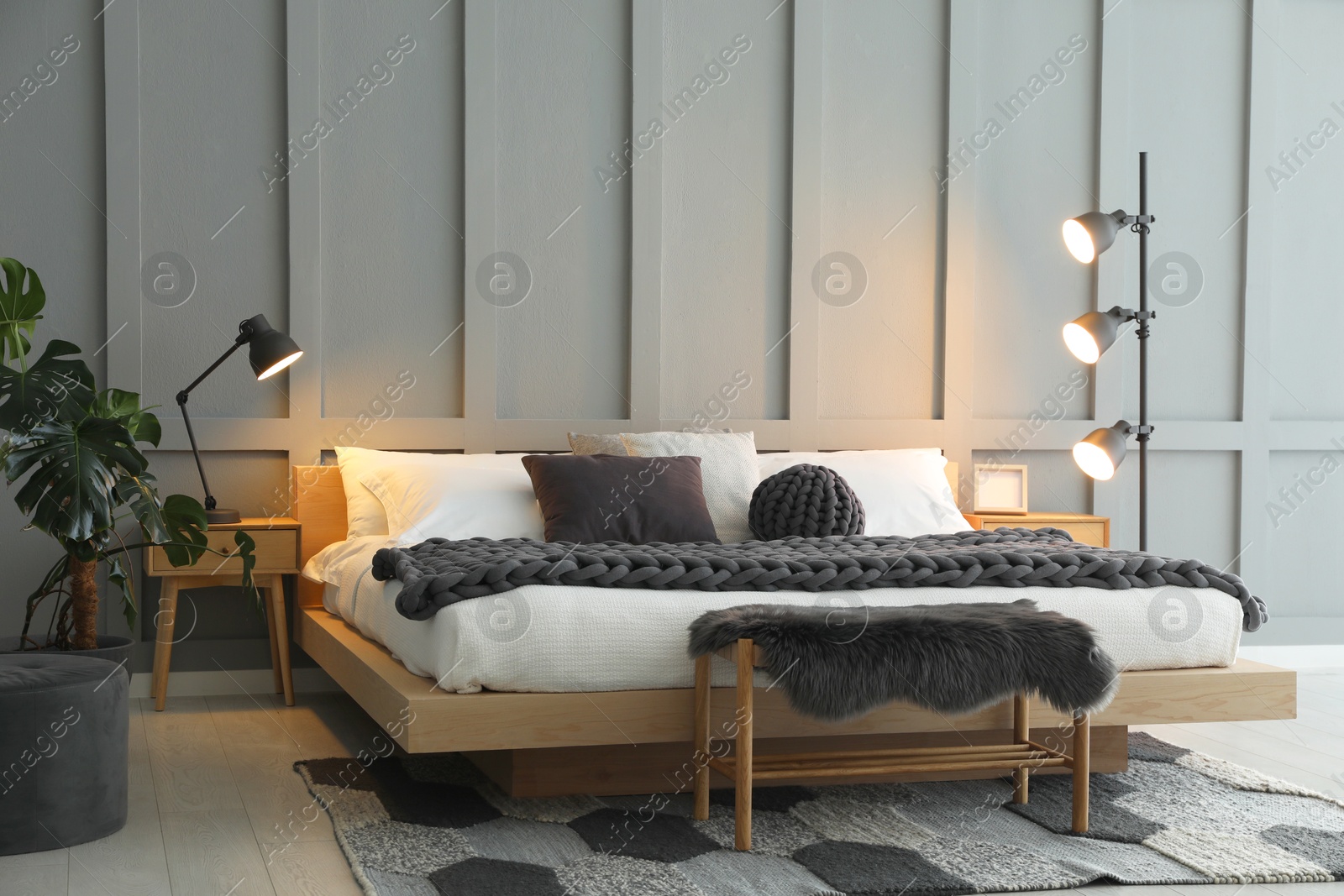 Photo of Stylish bedroom interior with comfortable bed, lamps and houseplant