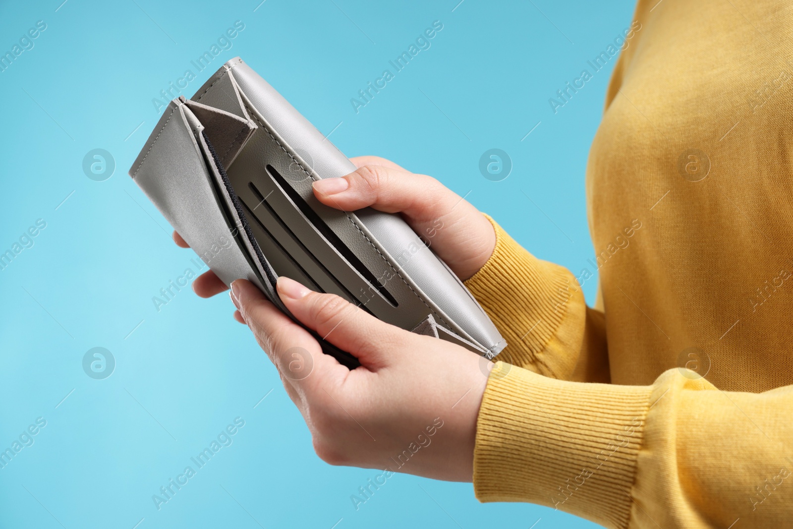 Photo of Woman with empty wallet on light blue background, closeup