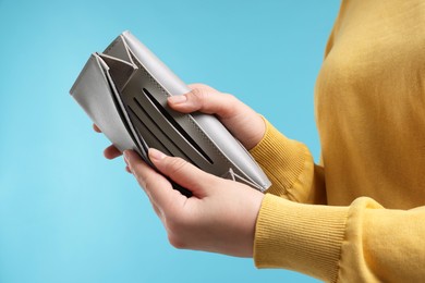 Photo of Woman with empty wallet on light blue background, closeup