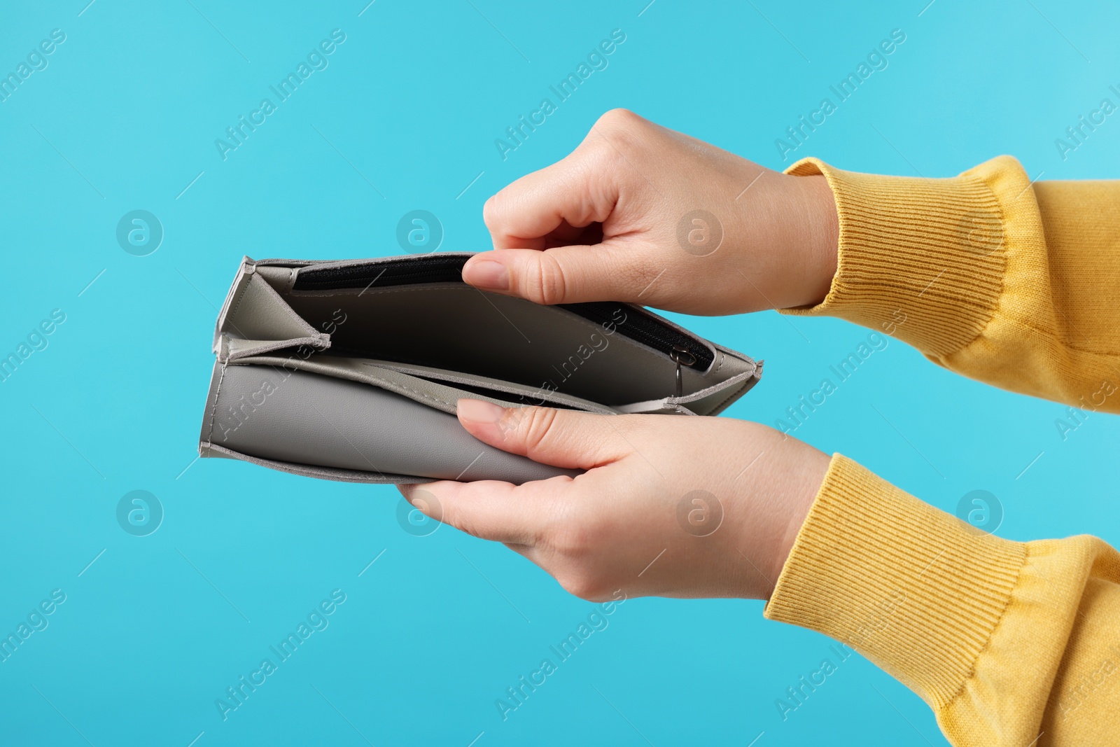 Photo of Woman with empty wallet on light blue background, closeup