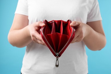 Photo of Woman with empty wallet on light blue background, closeup