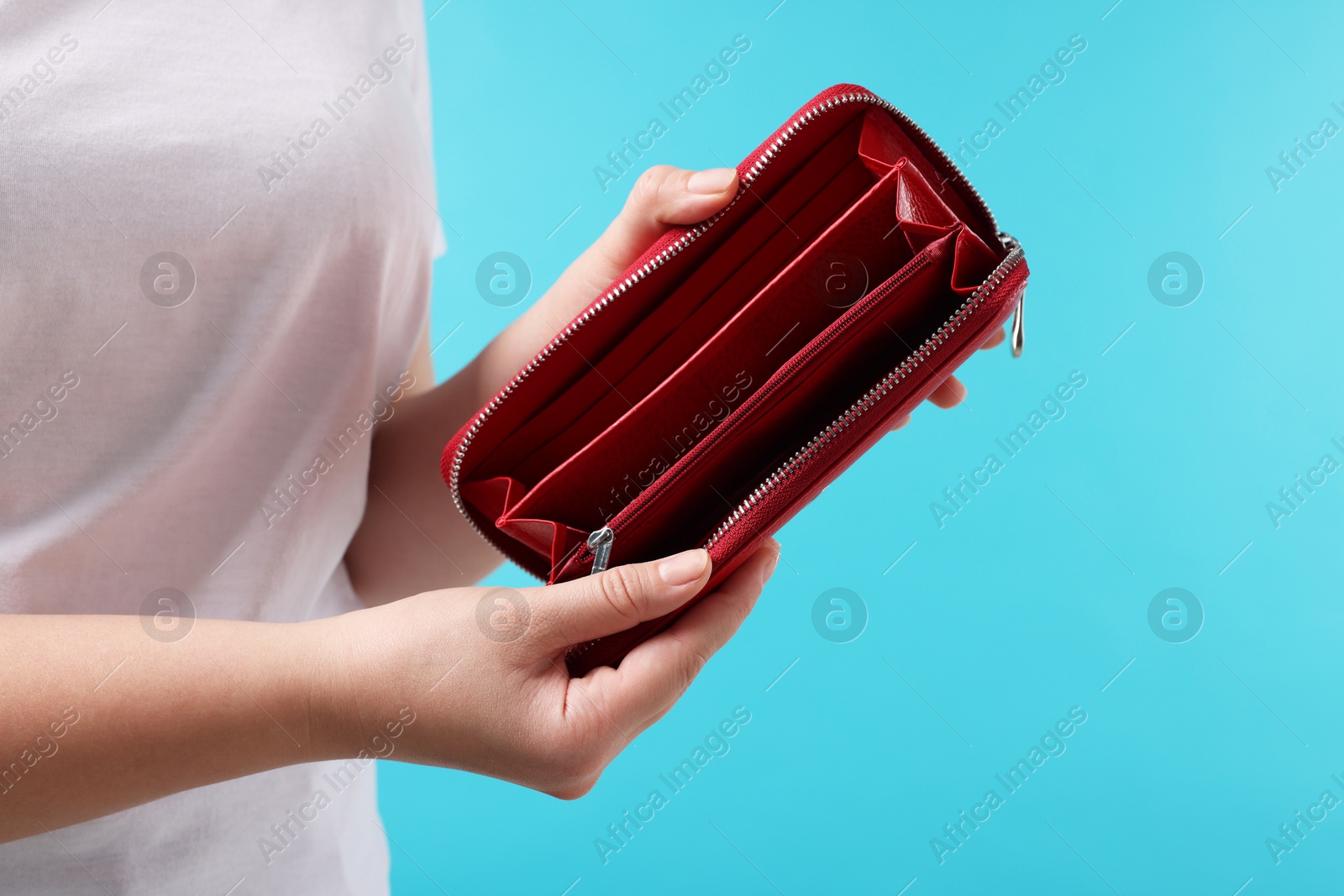 Photo of Woman with empty wallet on light blue background, closeup