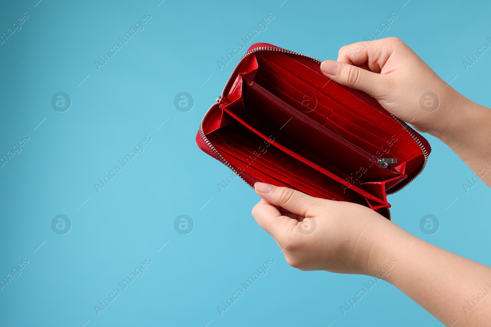 Photo of Woman with empty wallet on light blue background, closeup