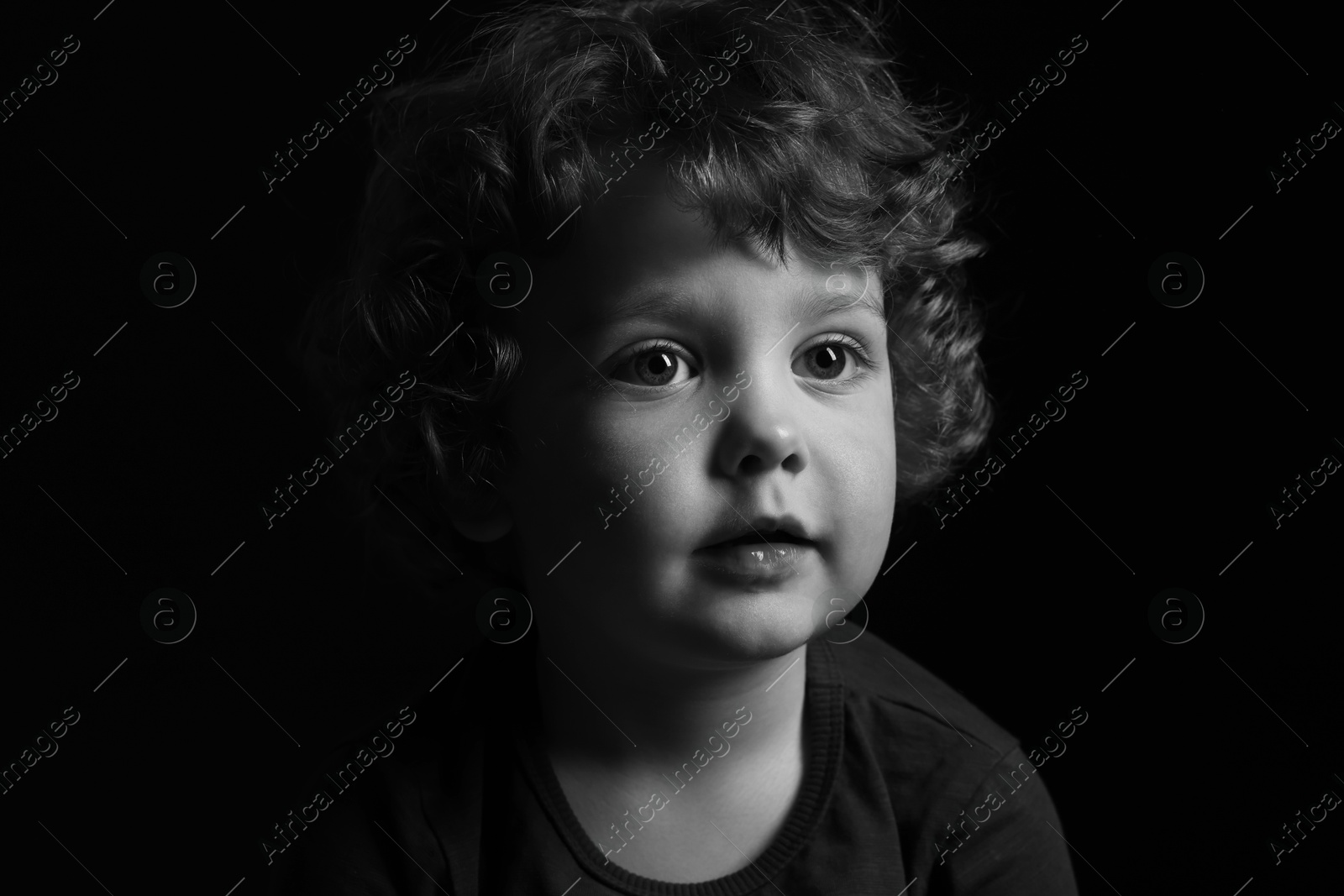 Photo of Portrait of cute little boy on dark background. Black and white effect