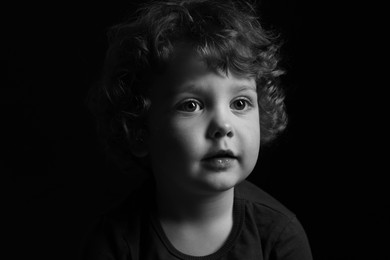 Portrait of cute little boy on dark background. Black and white effect