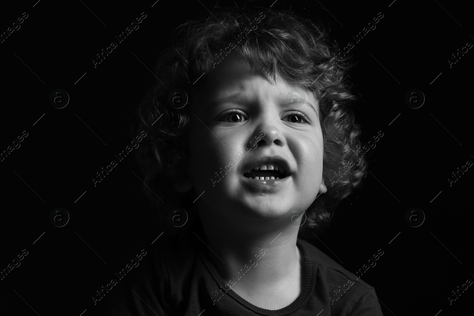 Photo of Portrait of sad little boy on dark background. Black and white effect