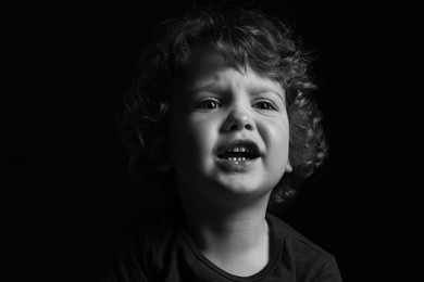 Photo of Portrait of sad little boy on dark background. Black and white effect