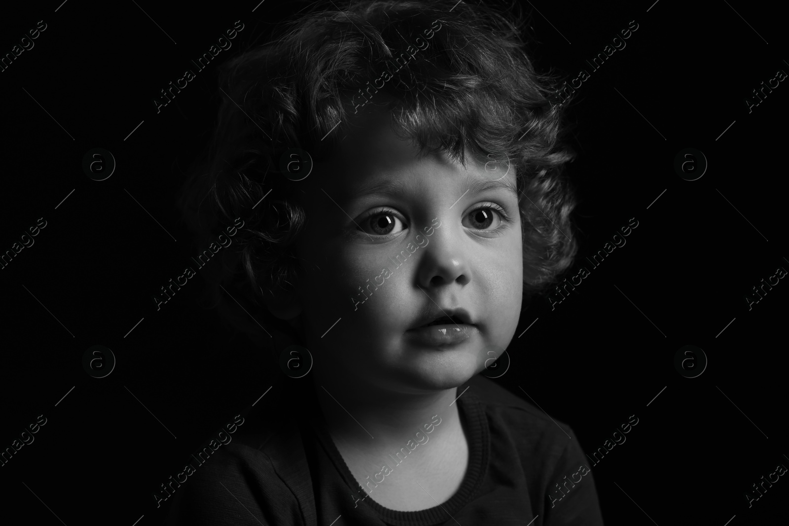 Photo of Portrait of cute little boy on dark background. Black and white effect