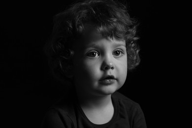 Photo of Portrait of cute little boy on dark background. Black and white effect