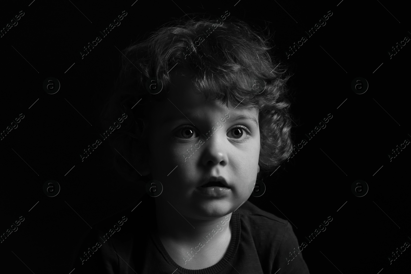 Photo of Portrait of cute little boy on dark background. Black and white effect