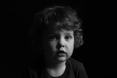 Photo of Portrait of cute little boy on dark background. Black and white effect