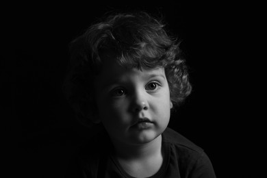 Portrait of cute little boy on dark background. Black and white effect