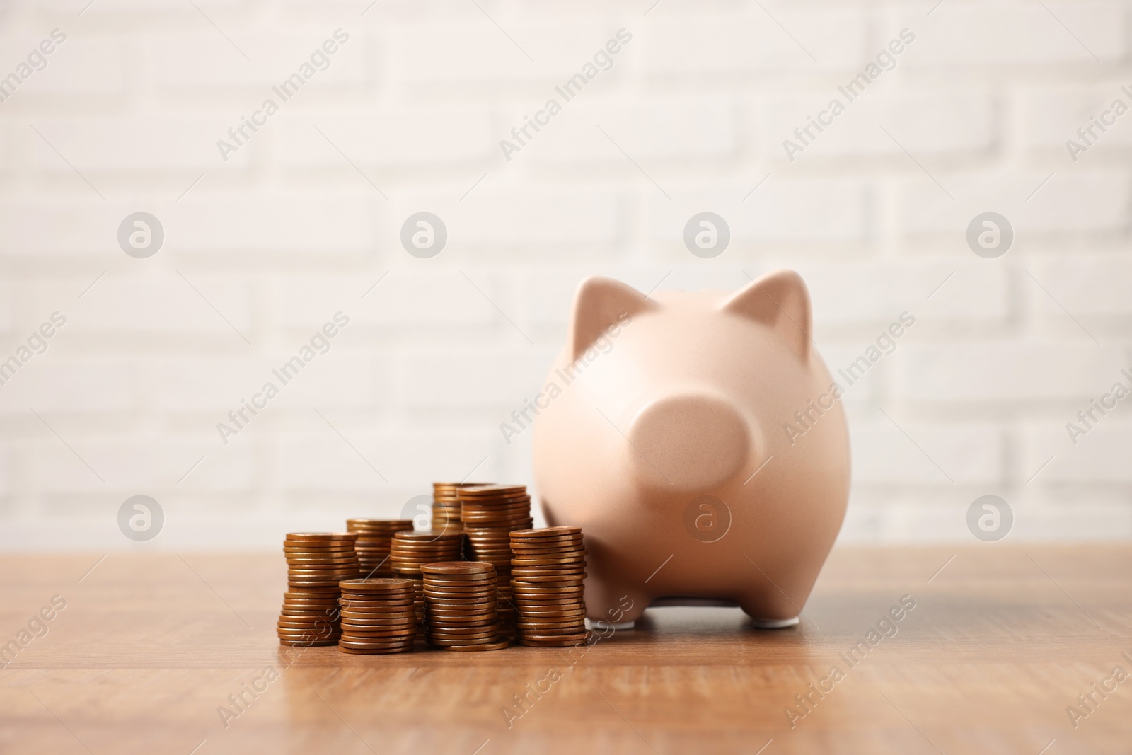 Photo of Piggy bank and stacks of coins on wooden table