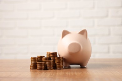 Piggy bank and stacks of coins on wooden table