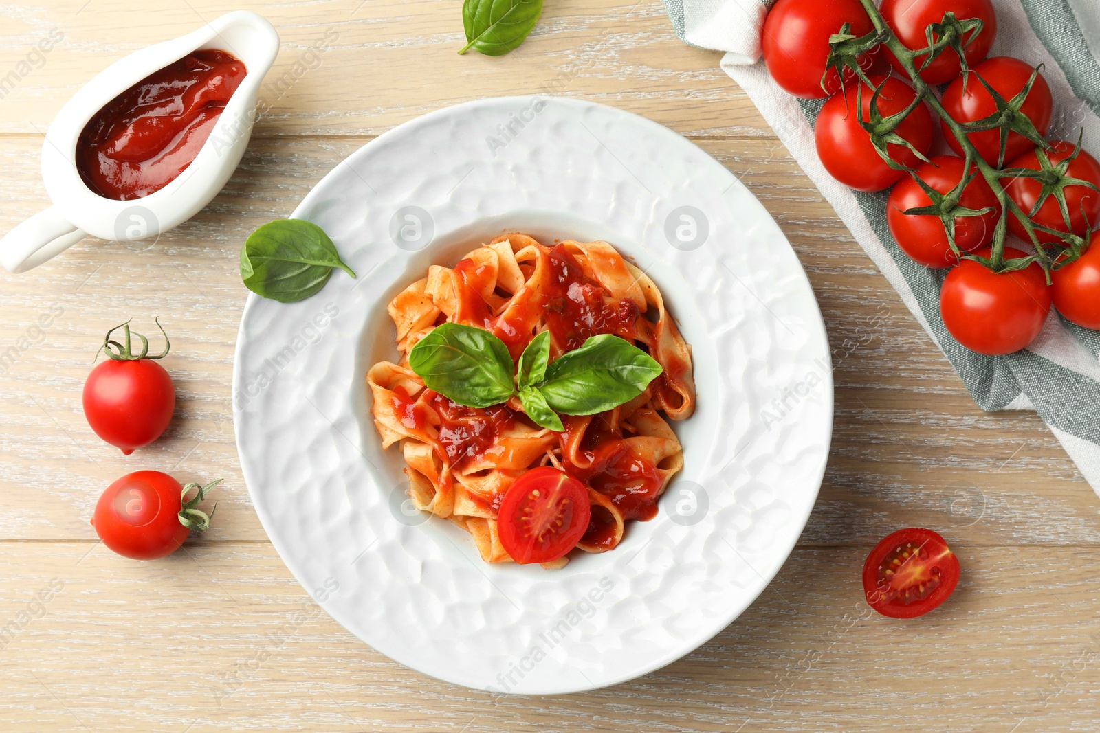 Photo of Delicious pasta with sauce, tomato and basil on wooden table, flat lay