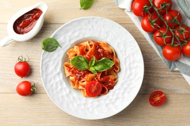 Delicious pasta with sauce, tomato and basil on wooden table, flat lay