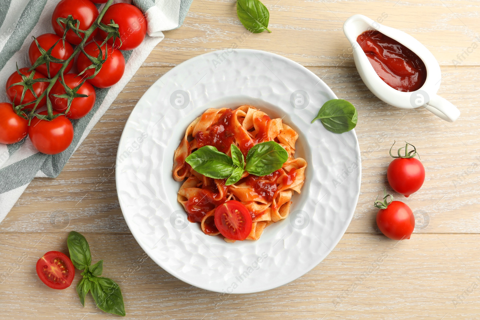 Photo of Delicious pasta with sauce, tomato and basil on wooden table, flat lay