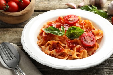 Delicious pasta with tomato sauce and basil on wooden table, closeup