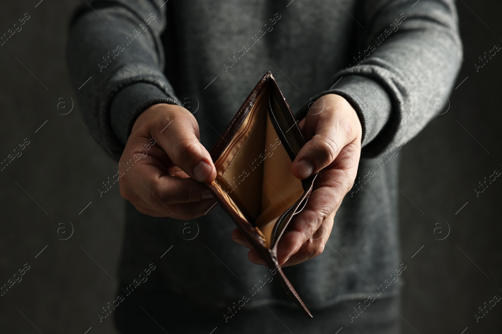 Photo of Man with empty wallet on dark background, closeup