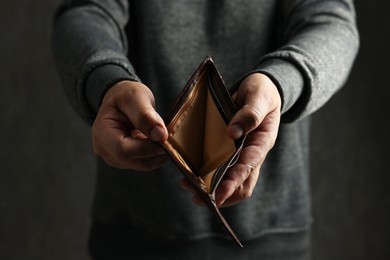 Photo of Man with empty wallet on dark background, closeup