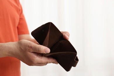 Photo of Man with empty wallet on blurred background, closeup. Space for text