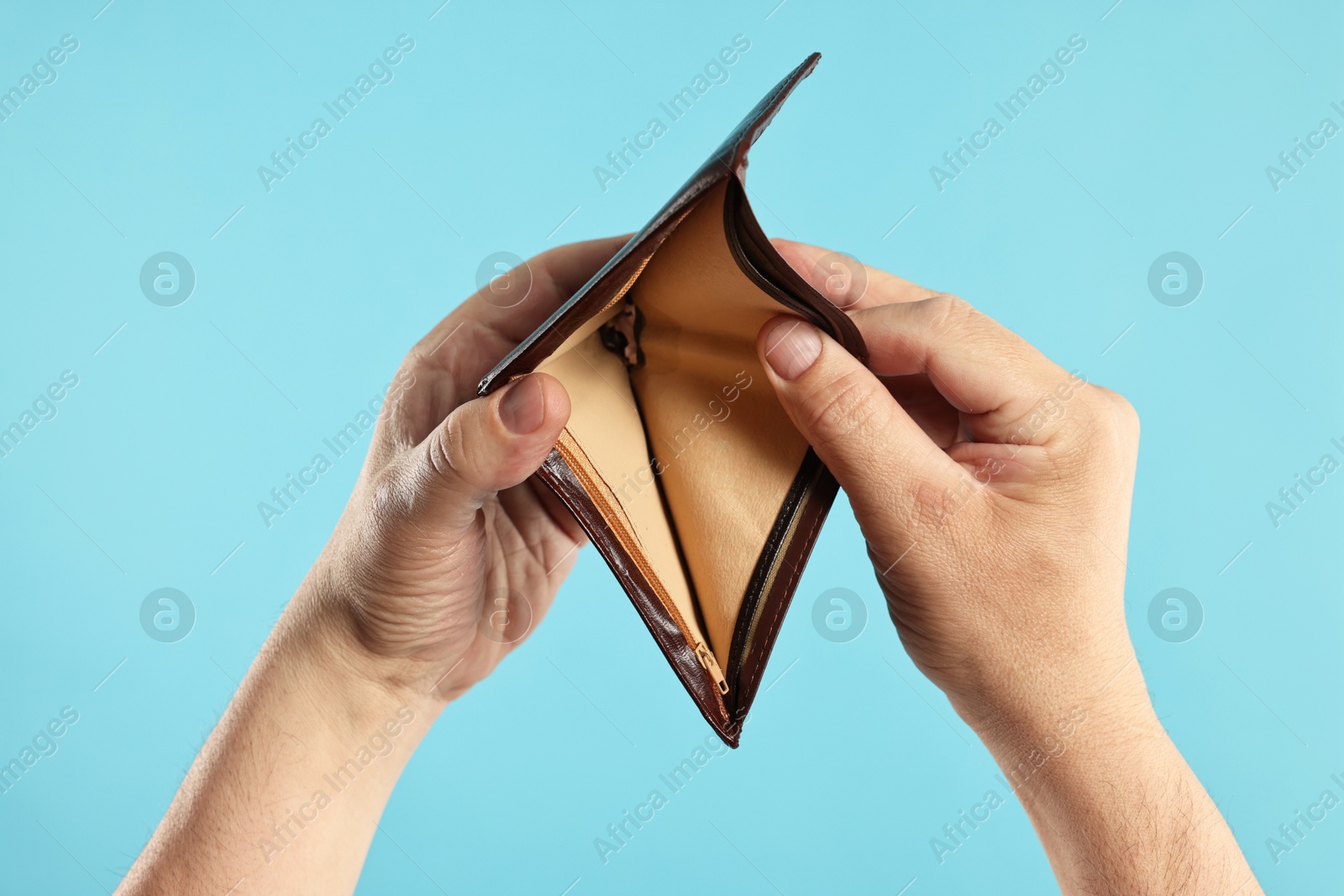 Photo of Man with empty wallet on light blue background, closeup