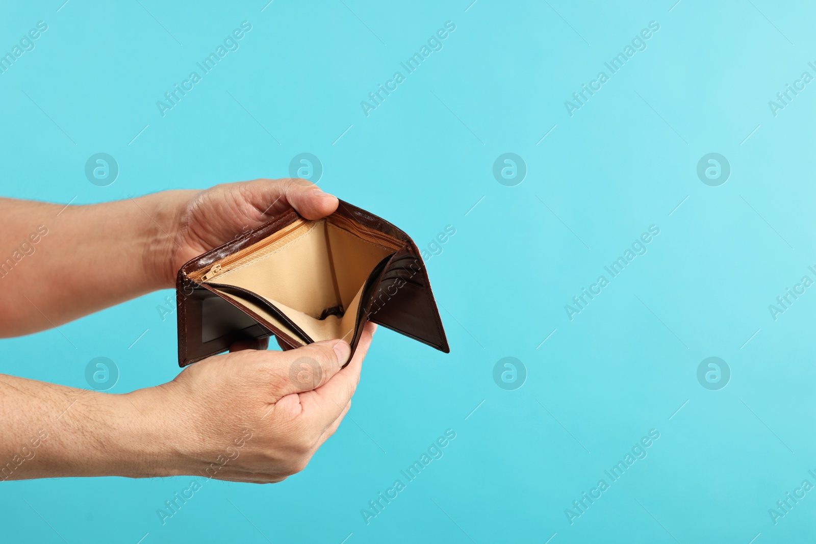 Photo of Man with empty wallet on light blue background, closeup. Space for text