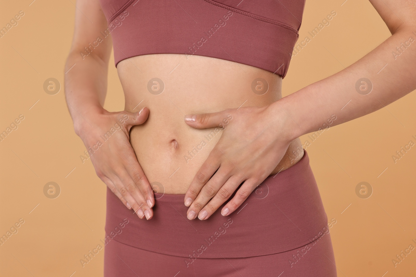 Photo of Healthy digestion. Woman touching her belly on beige background, closeup