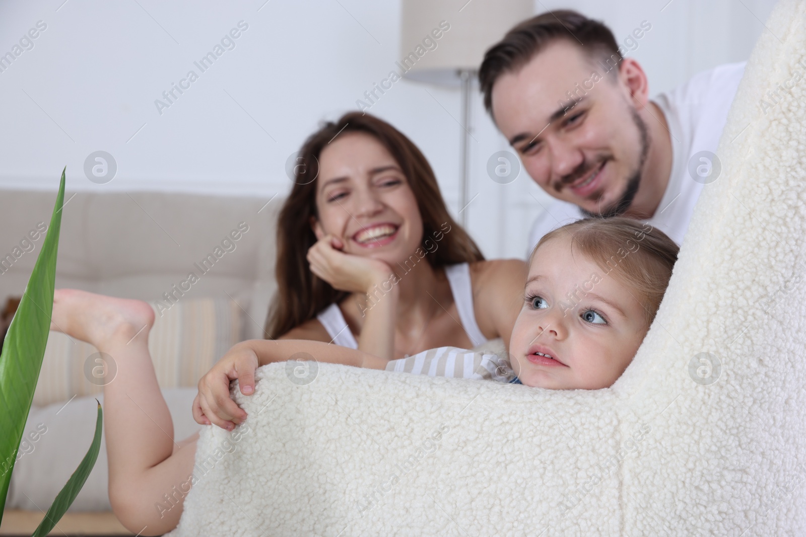 Photo of Happy family. Parents and their cute little daughter in armchair at home, selective focus