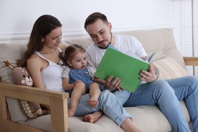 Happy family. Parents and their cute little daughter reading book at home