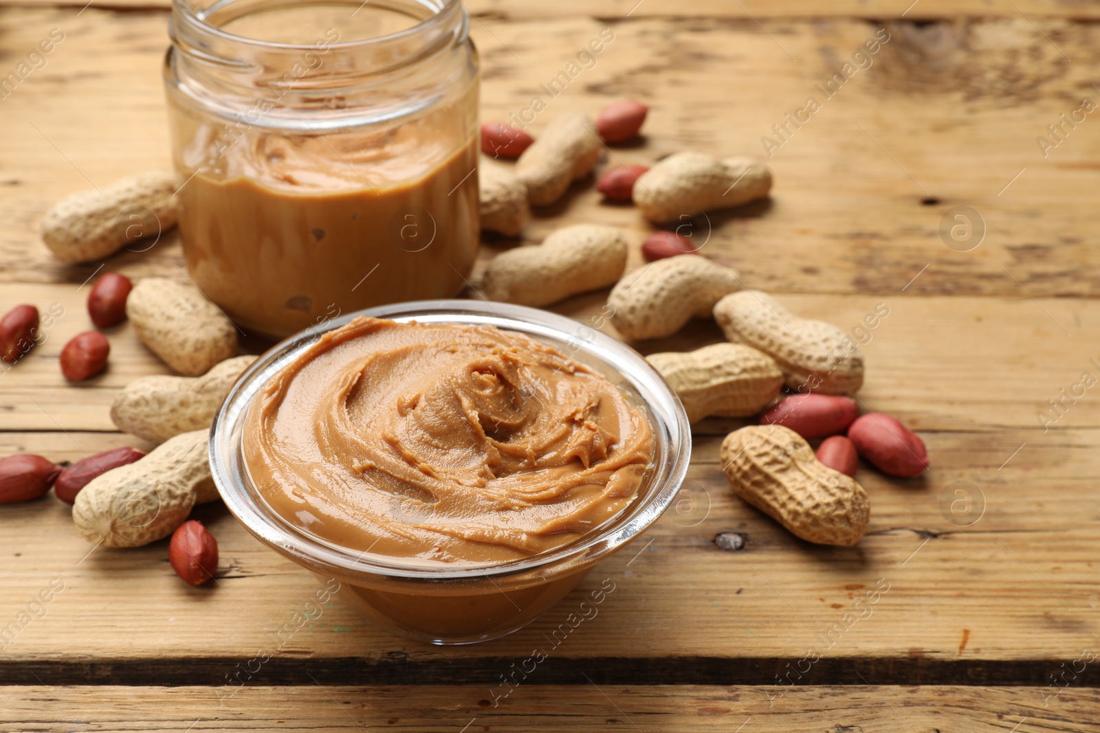 Photo of Tasty peanut butter and groundnuts on wooden table