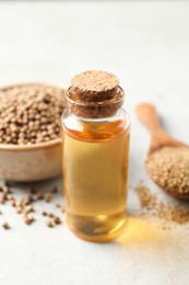 Photo of Coriander essential oil, powder and seeds on light grey table