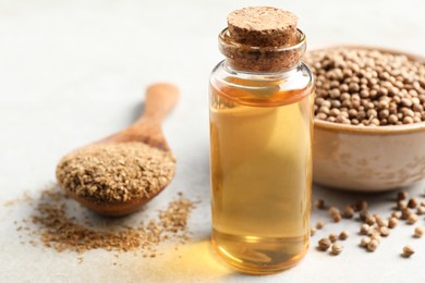 Photo of Coriander essential oil, powder and seeds on light grey table