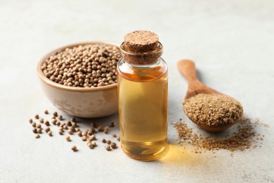 Coriander essential oil, powder and seeds on light grey table