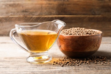 Dried coriander seeds in bowl and oil on wooden table