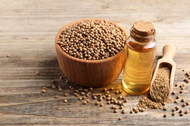 Photo of Coriander essential oil, powder and seeds on wooden table