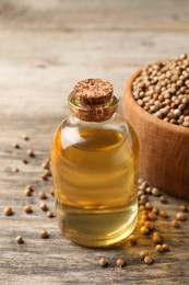 Coriander essential oil and seeds on wooden table