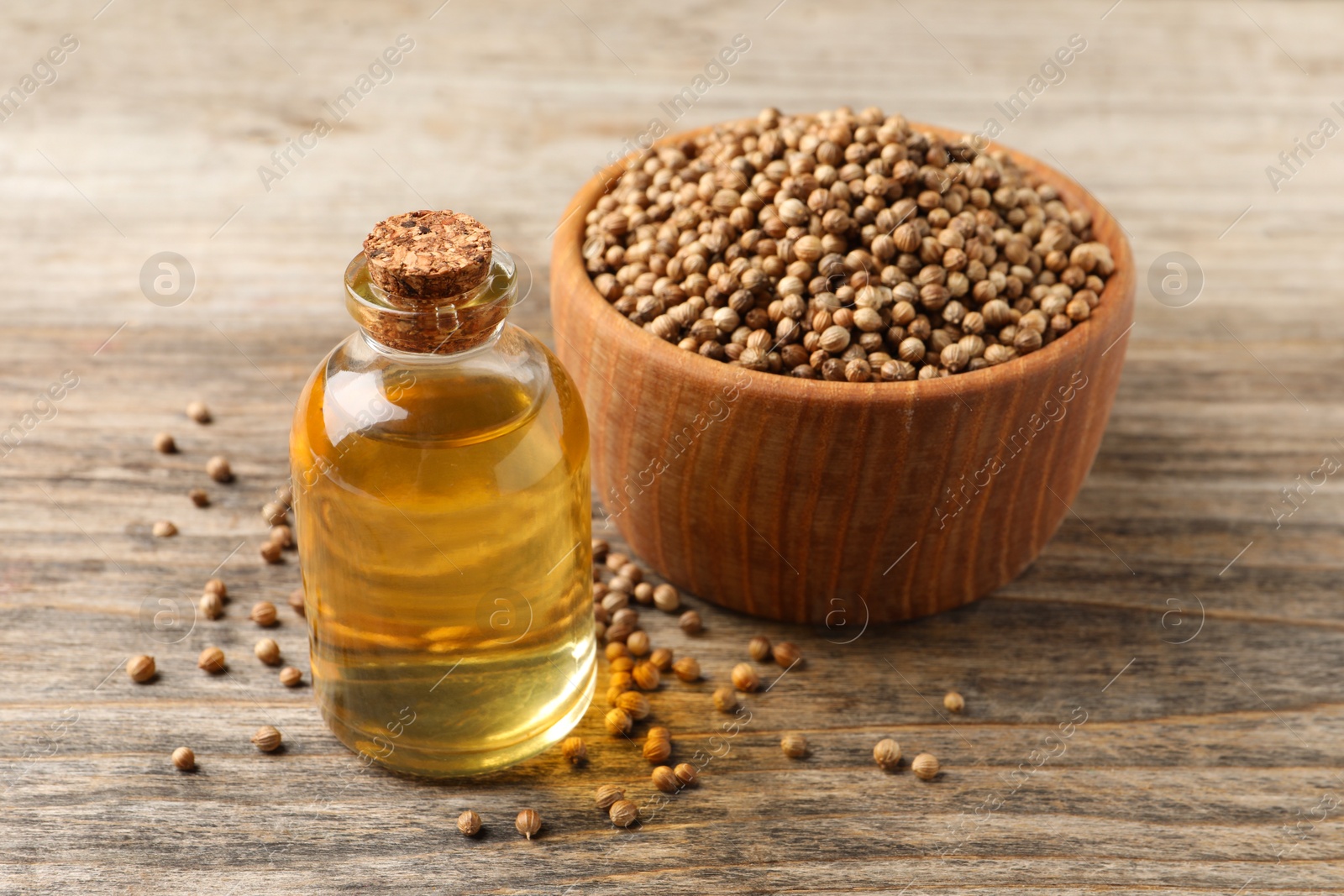 Photo of Coriander essential oil and seeds on wooden table