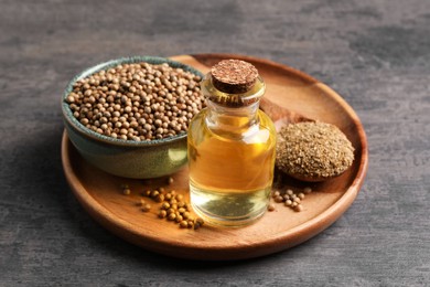 Coriander essential oil, seeds and powder on grey table