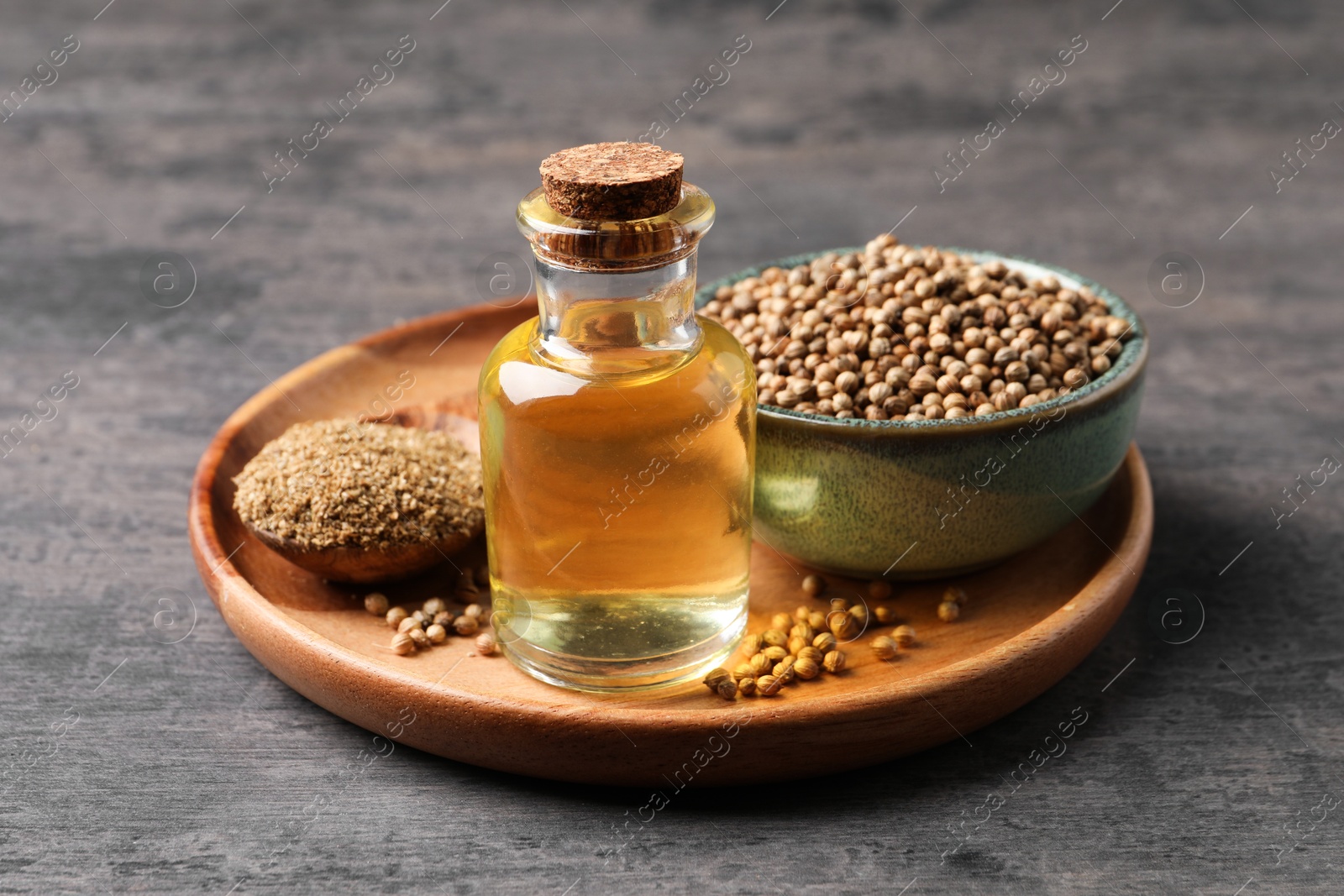 Photo of Coriander essential oil, seeds and powder on grey table